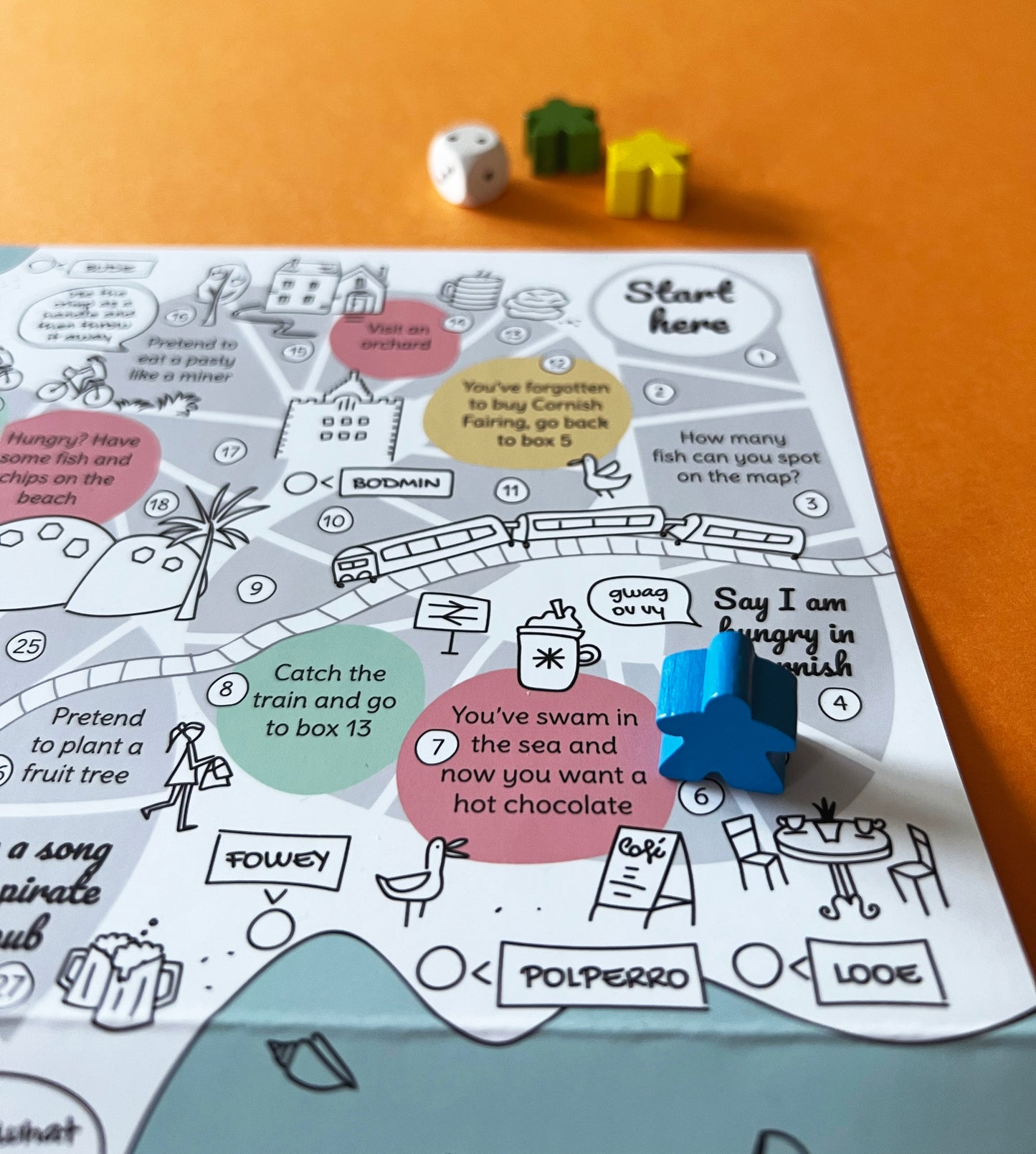 Strolling Cornwall Food Edition with wooden dice and markers. Illustration of the train, seagull, Fowey, Polperro and Looe.
