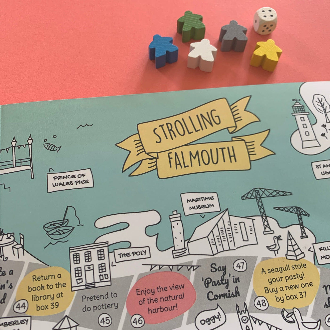 Detail of Strolling Falmouth board game with wooden dice and markers, o red background.